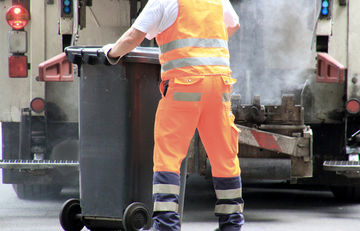 Müllwerker mit Restmülltonne