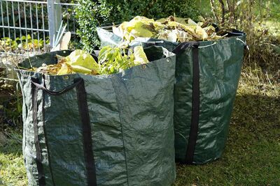 zwei grüne Plastiksäcke gefüllt mit Gartenabfällen